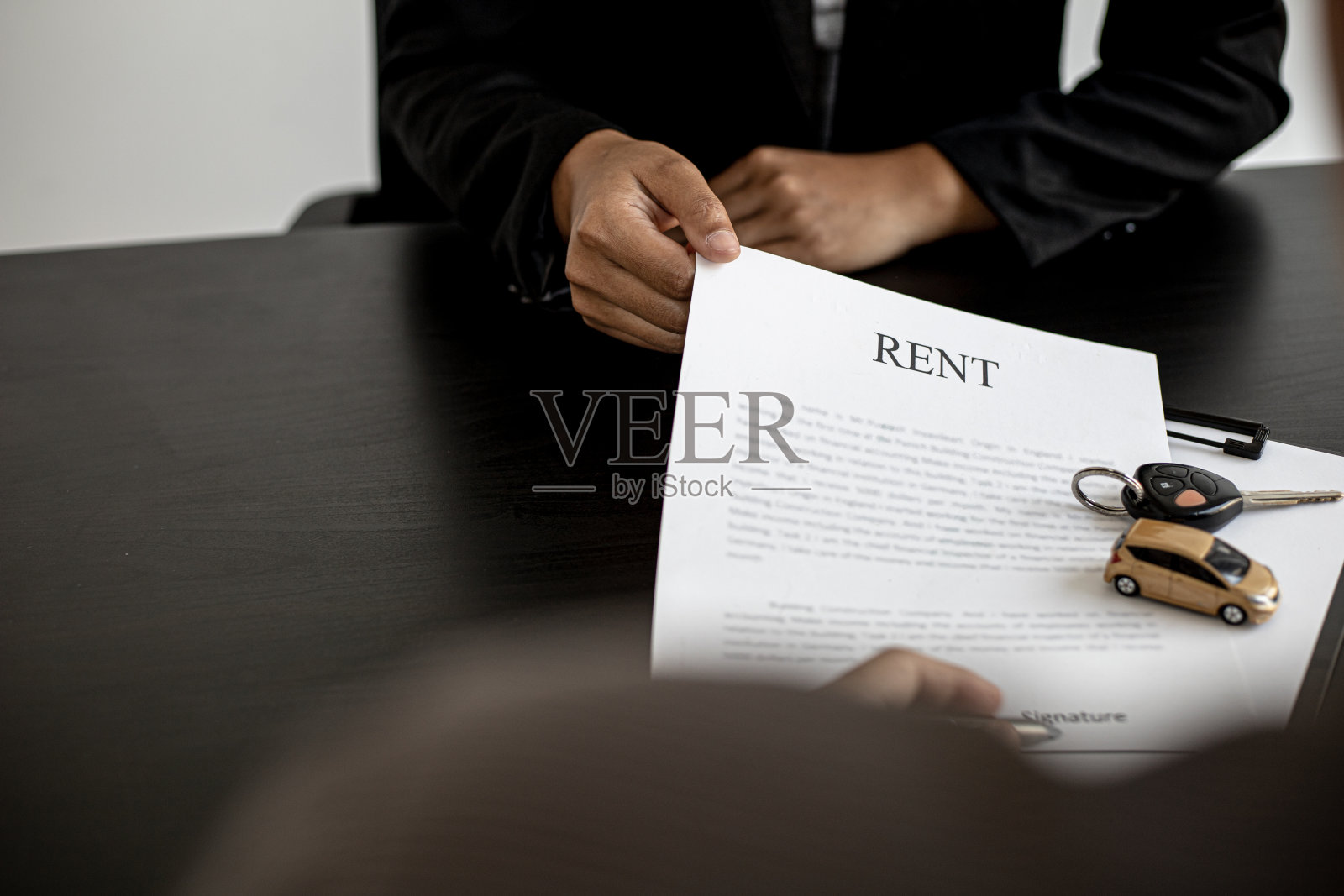 汽车租赁公司的员工提交一份汽车租赁协议，与租赁人讨论租车细节后签订租赁协议。汽车租赁的概念。照片摄影图片