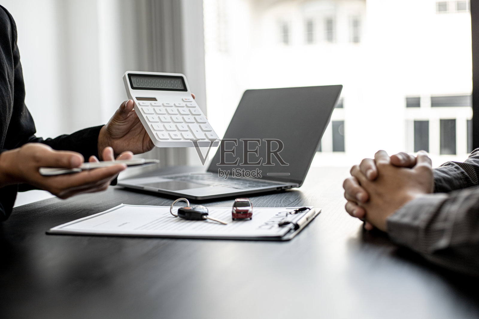 一个汽车租赁公司的员工拿着一个白色计算器向租客显示租金，员工在与租客签订租赁协议之前计算租车的费用。照片摄影图片