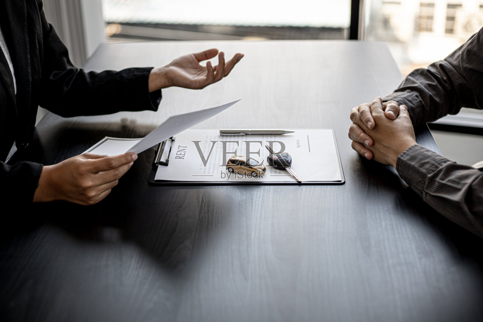 汽车租赁公司的一名员工正在为租车人解释租车公司的细节和条件，并准备租车合同文件。汽车租赁的概念。照片摄影图片