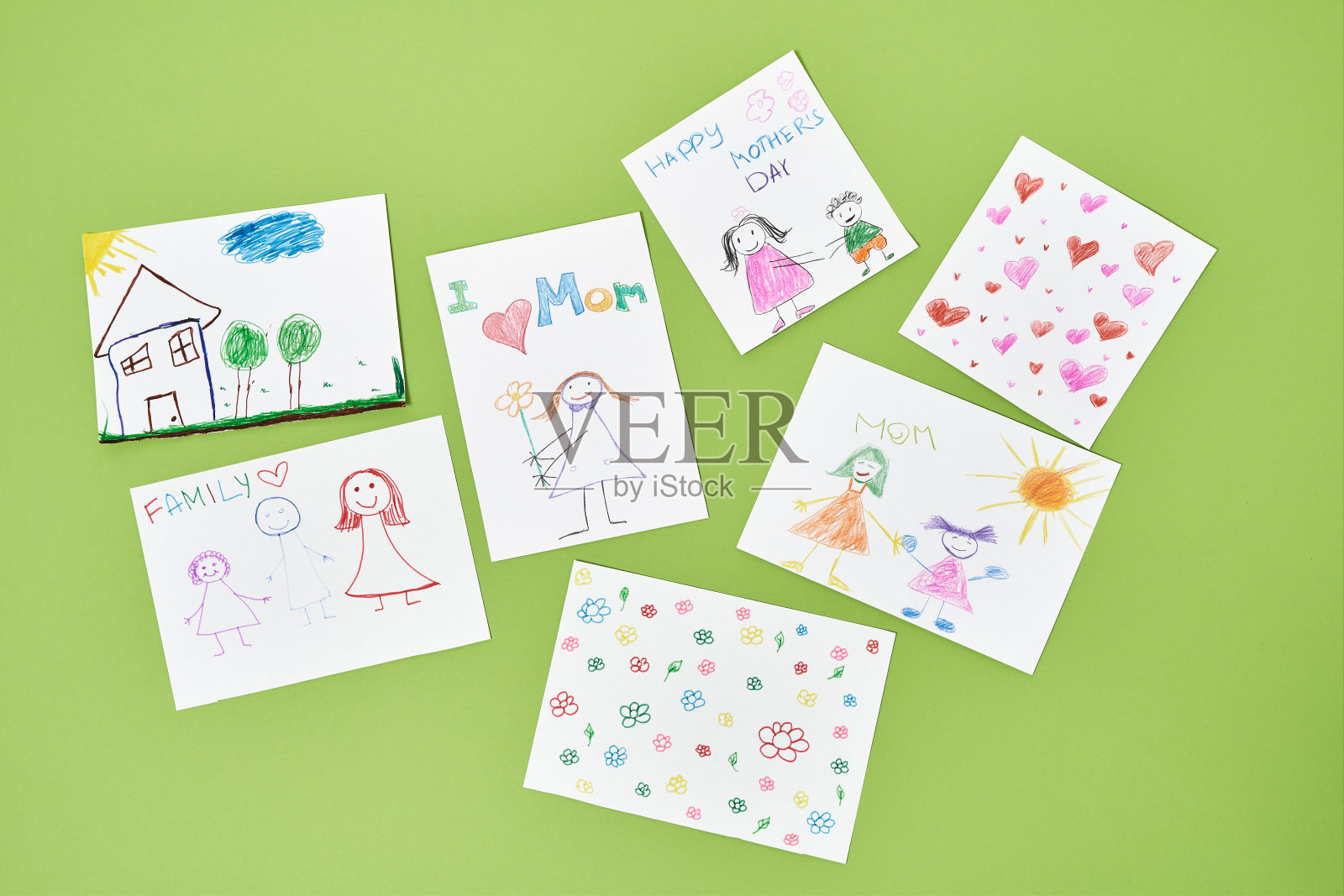 为了世界上最好的妈妈。俯视图彩色儿童绘画与彩色铅笔母亲节在绿色的背景，手工贺卡从孩子照片摄影图片