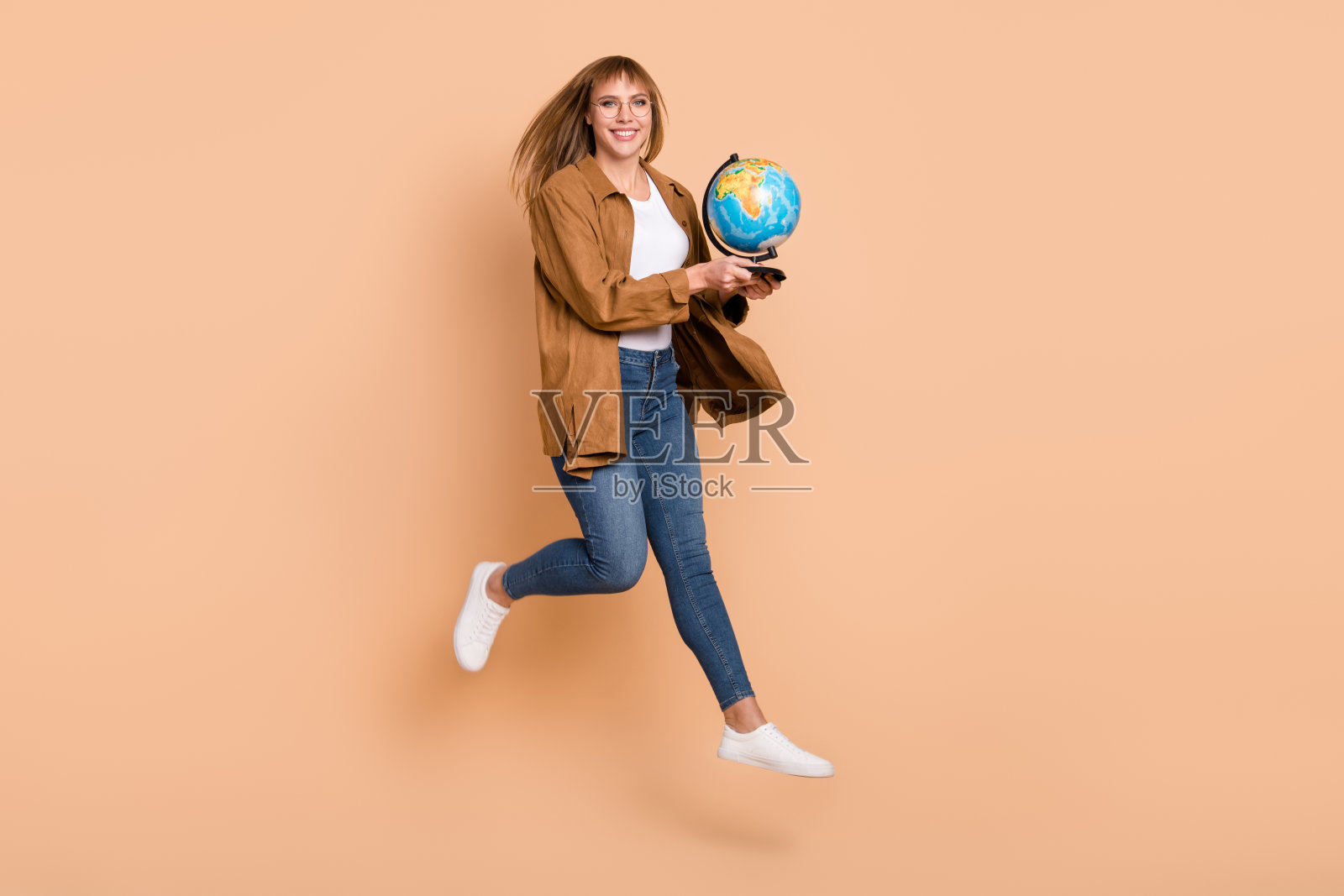 全尺寸的照片，年轻的快乐的女孩在眼镜跳保持地球仪地球孤立在柔和的颜色背景照片摄影图片