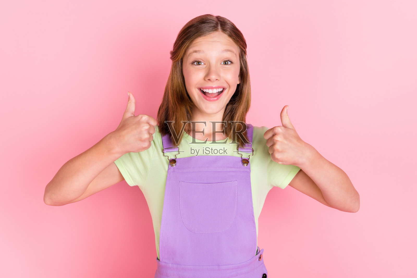 小女孩微笑的照片肖像显示大拇指像标志孤立在柔和的粉红色背景照片摄影图片