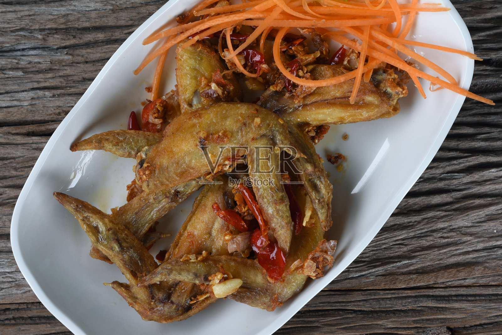 顶视图的炸鸡翅与大蒜，干辣椒和切片胡萝卜，在白色盘子照片摄影图片