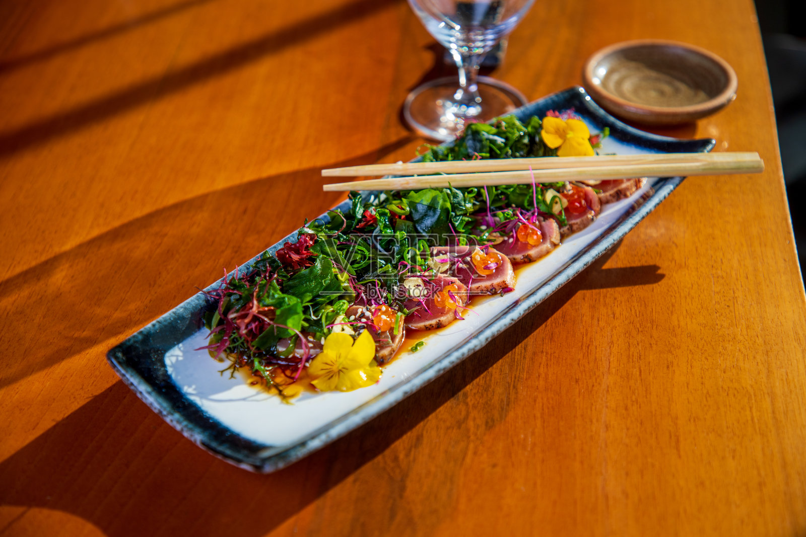 金枪鱼tataki切片与可食用的海藻，芝麻和鱼子酱，酱油在碗，筷子在盘子照片摄影图片