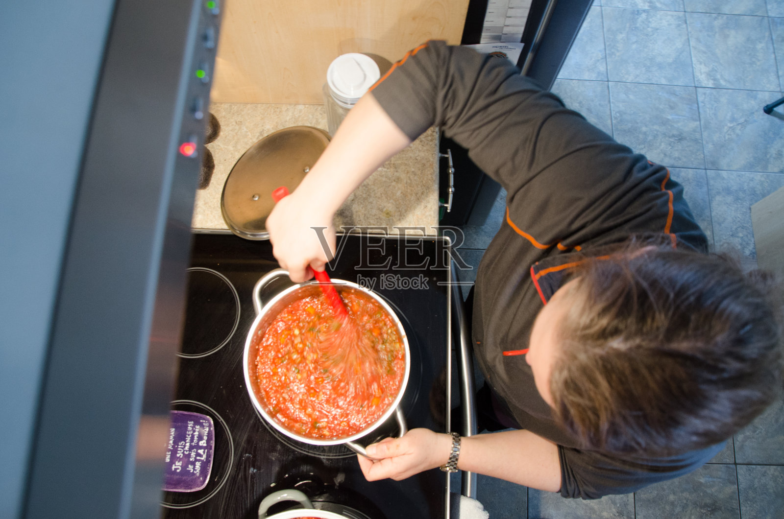 一个女人在烤箱上煮意大利面酱照片摄影图片