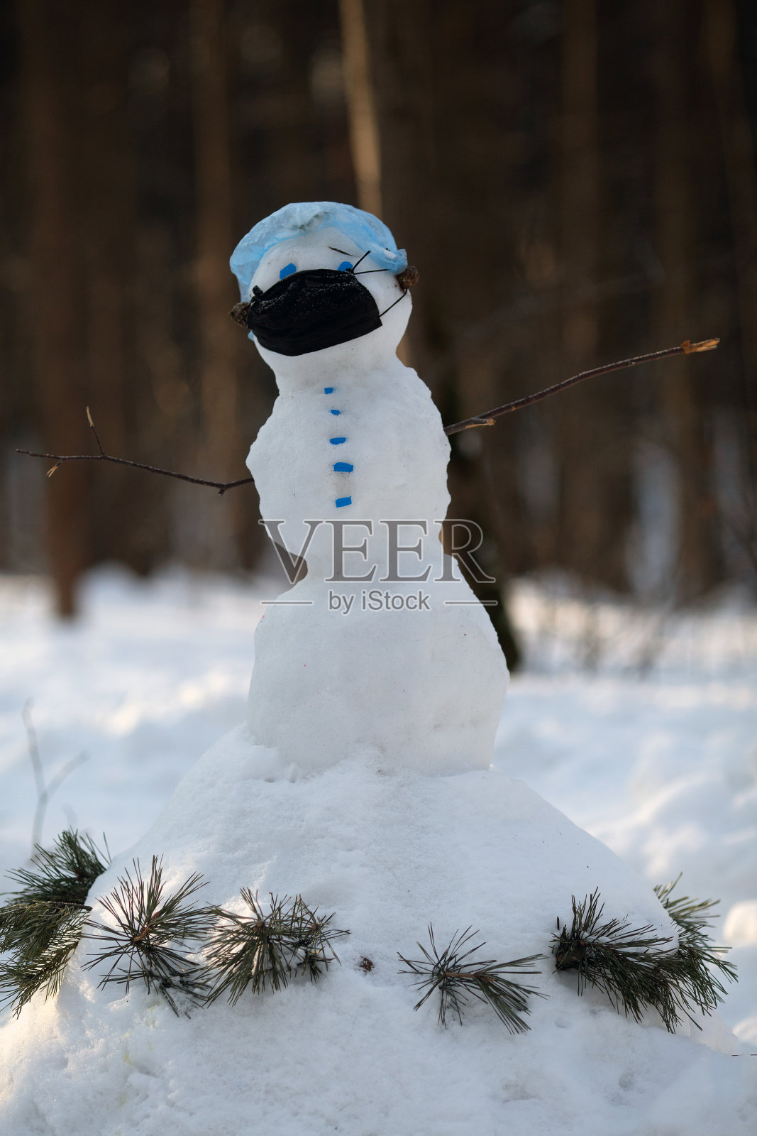 戴着防护面罩的雪人。2019冠状病毒病与隔离概念。照片摄影图片