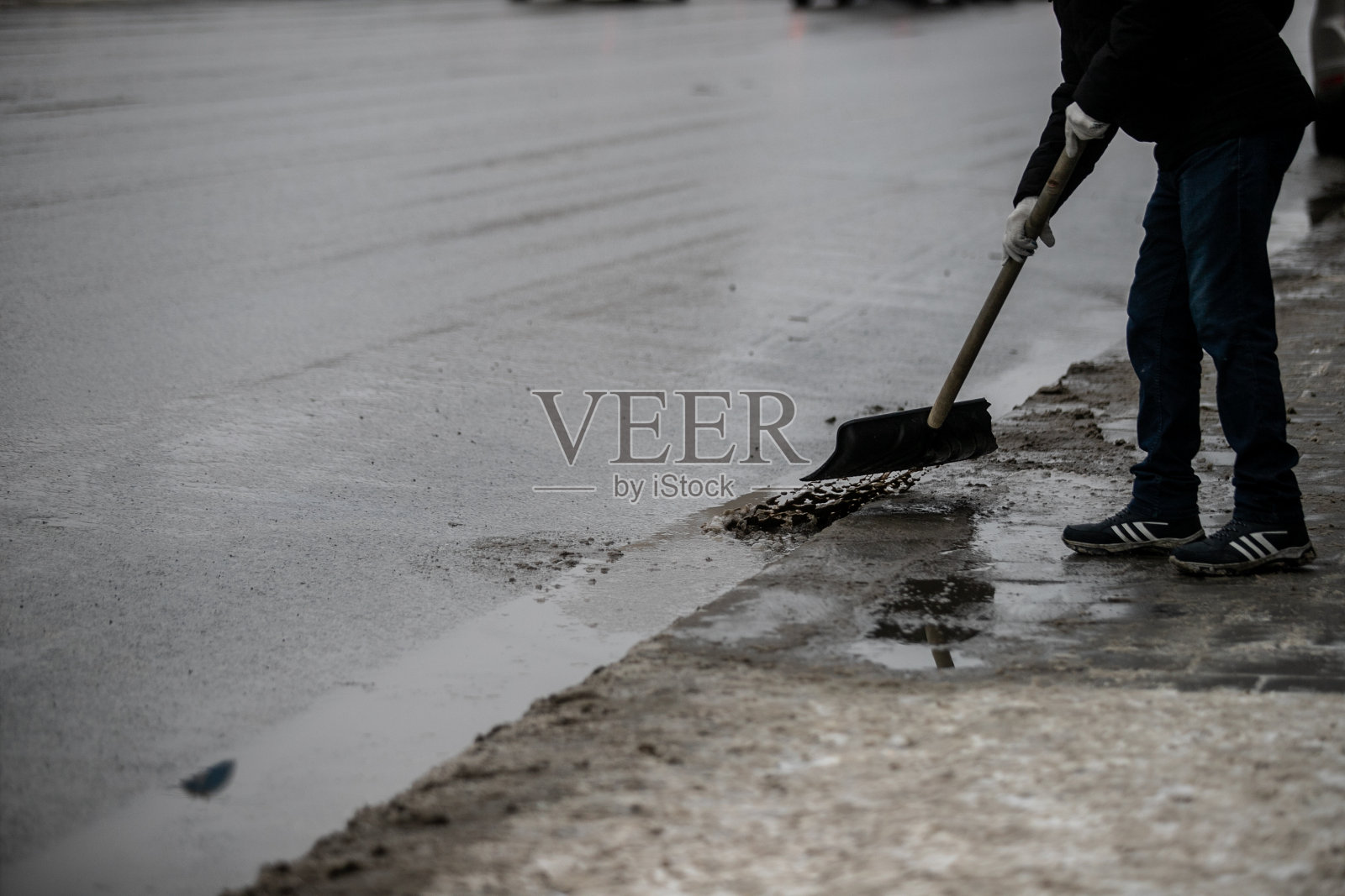 泥浆。在一个早春的日子里，沥青路上覆盖着正在融化的脏雪和泥。路上的雪还没有清除。春天解冻。雪融化。公路中间有个大泥坑。照片摄影图片