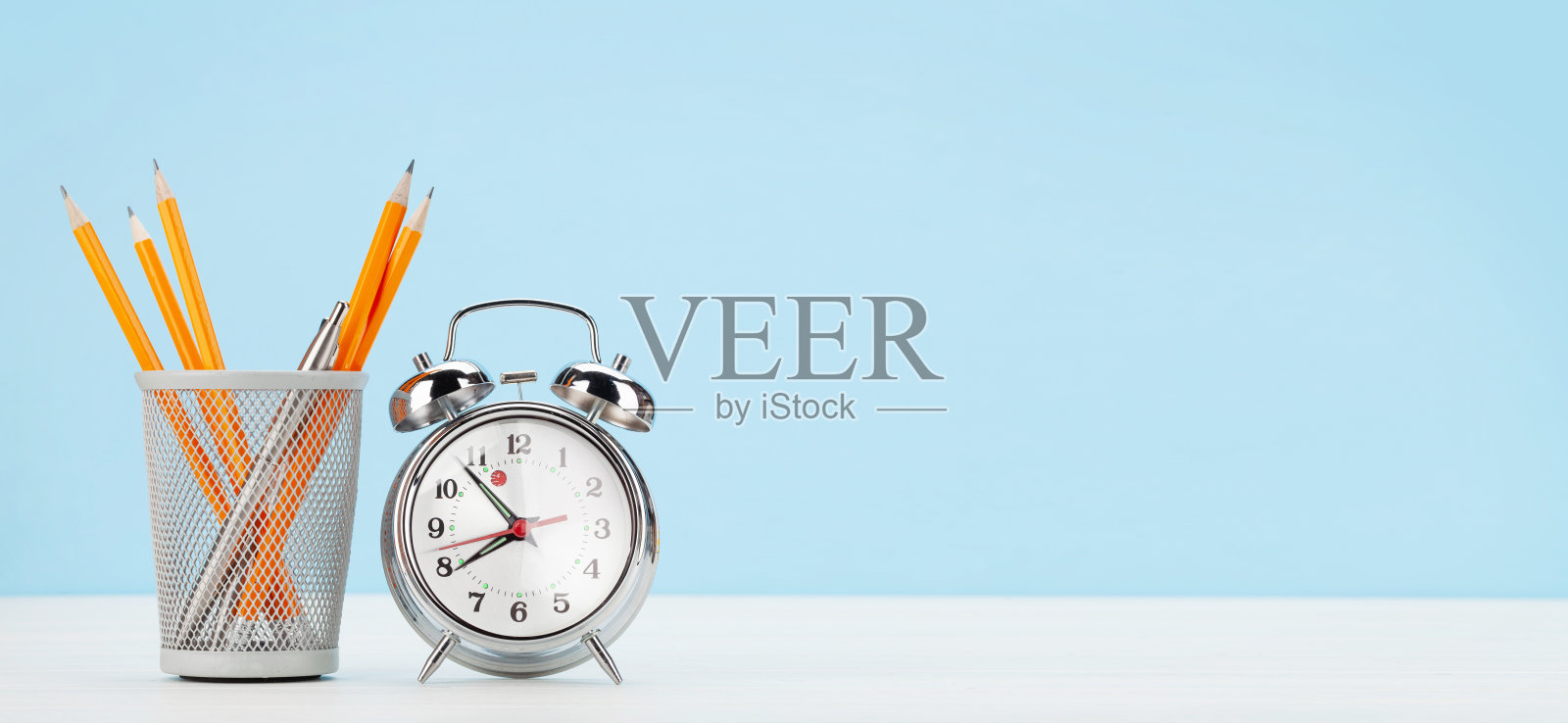 配有闹钟和办公用品的办公桌。居家办公照片摄影图片