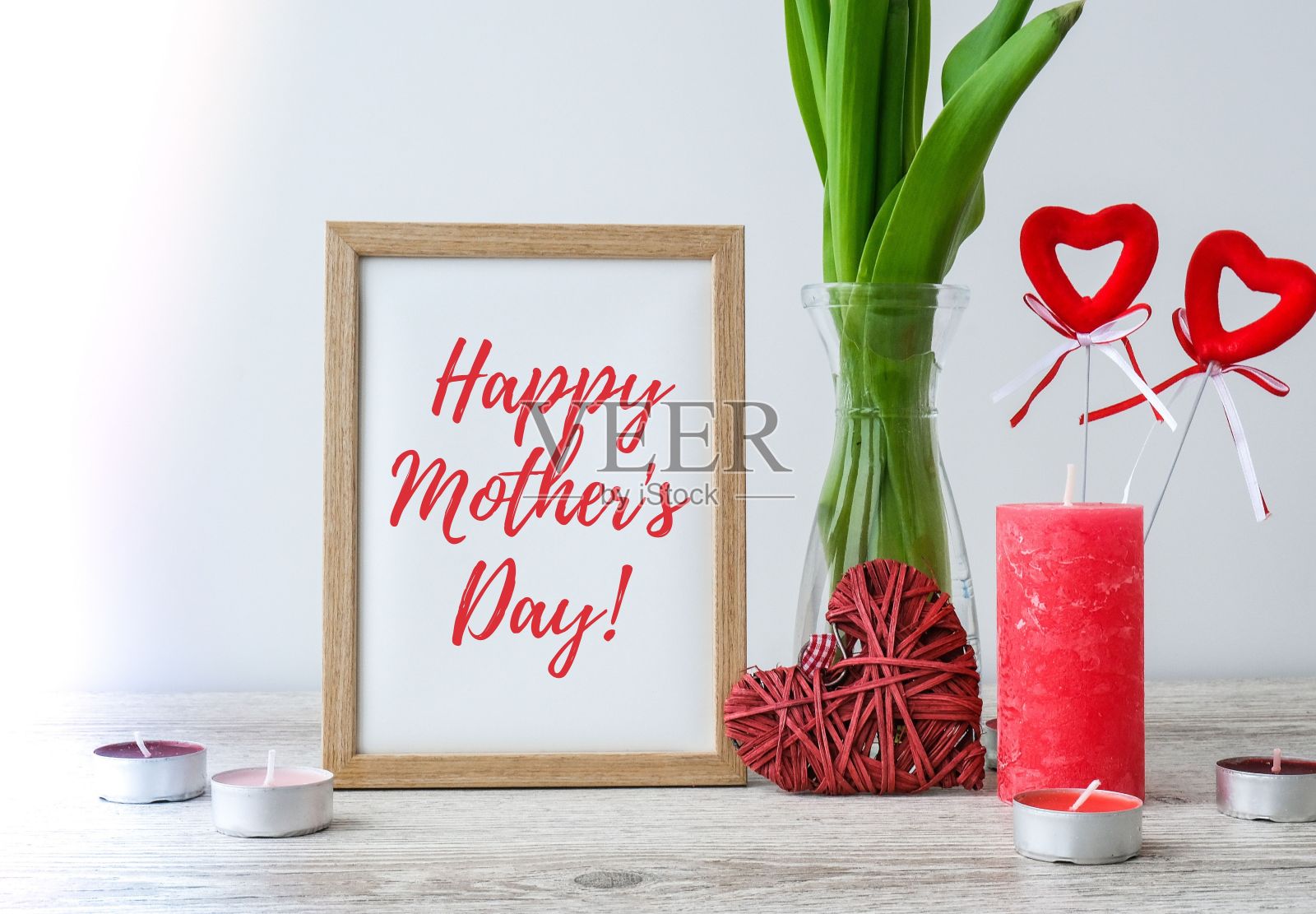 短信祝福母亲节贺卡。假期的模拟。郁金香花在玻璃花瓶与画框装饰的木桌背景墙在家里，近照片摄影图片