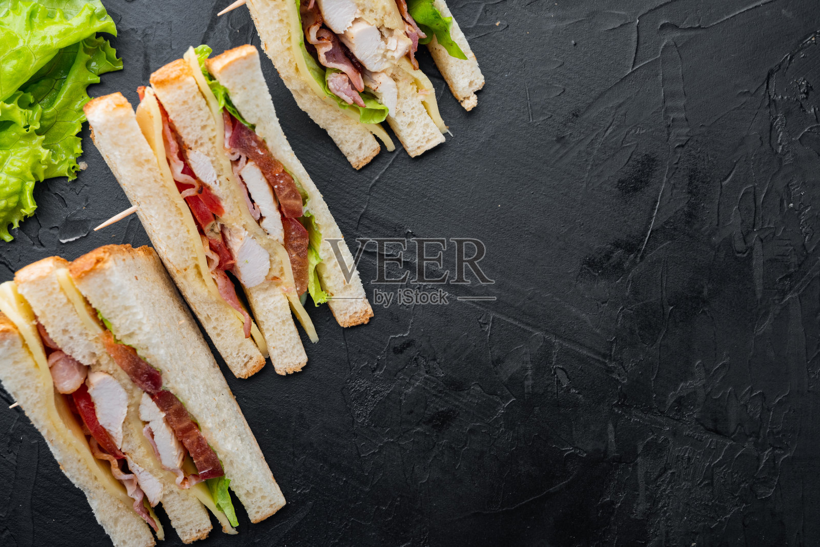 三明治与火腿，奶酪，番茄，生菜，鸡肉和烤面包，在黑色背景，俯视图与文本空间照片摄影图片