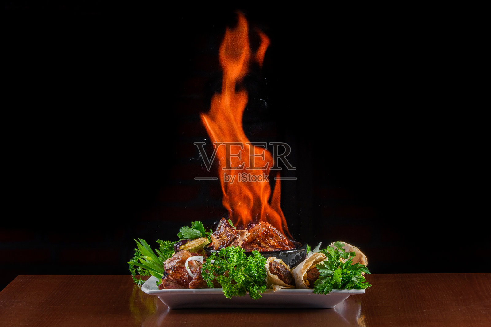 用陶碗把肉烤焦。火盘肉配烤蔬菜，皮塔饼烤肉串配香草装饰。照片摄影图片