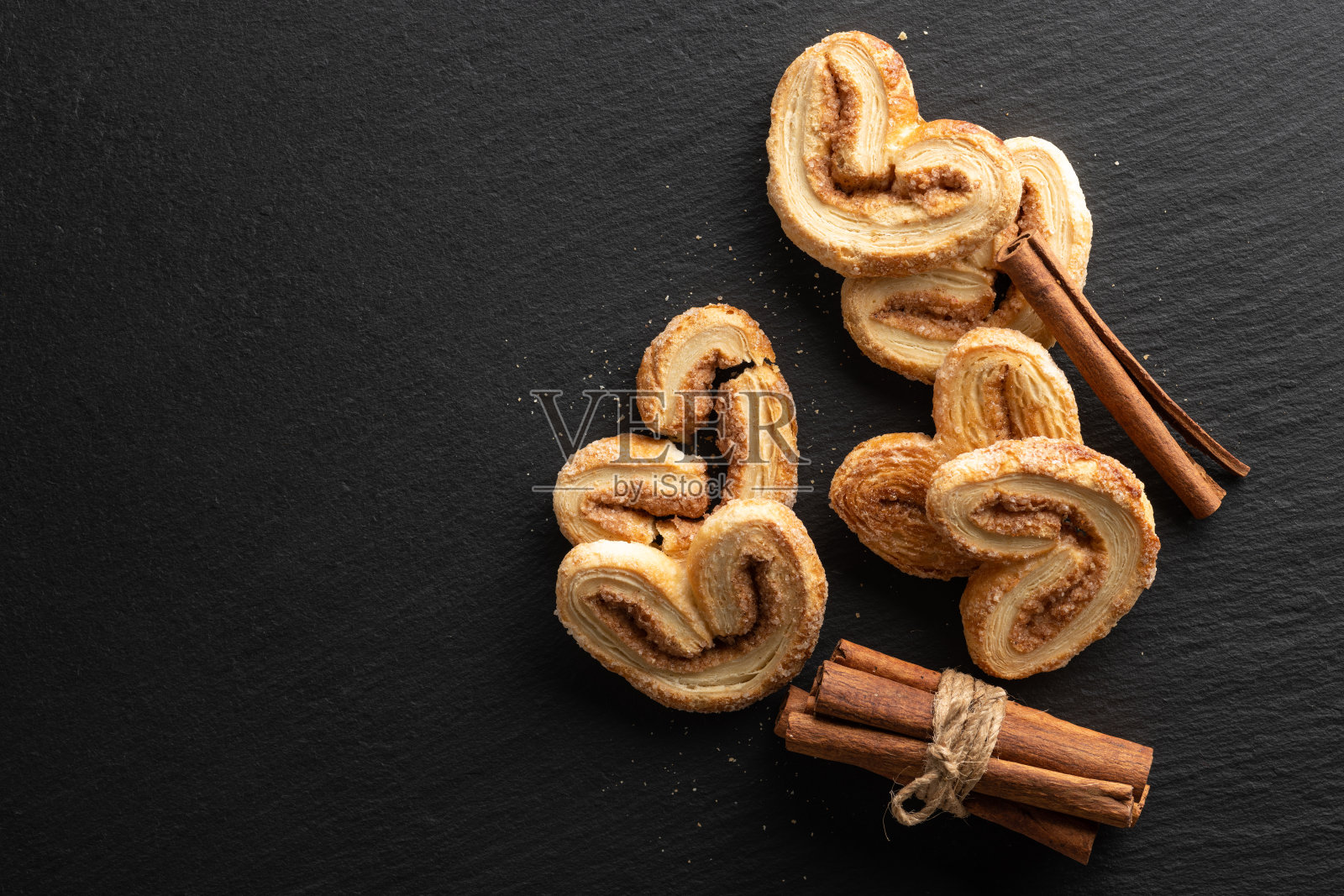 松脆的松饼与糖和肉桂在一个黑色的石头背景，俯视图，地方的文字照片摄影图片