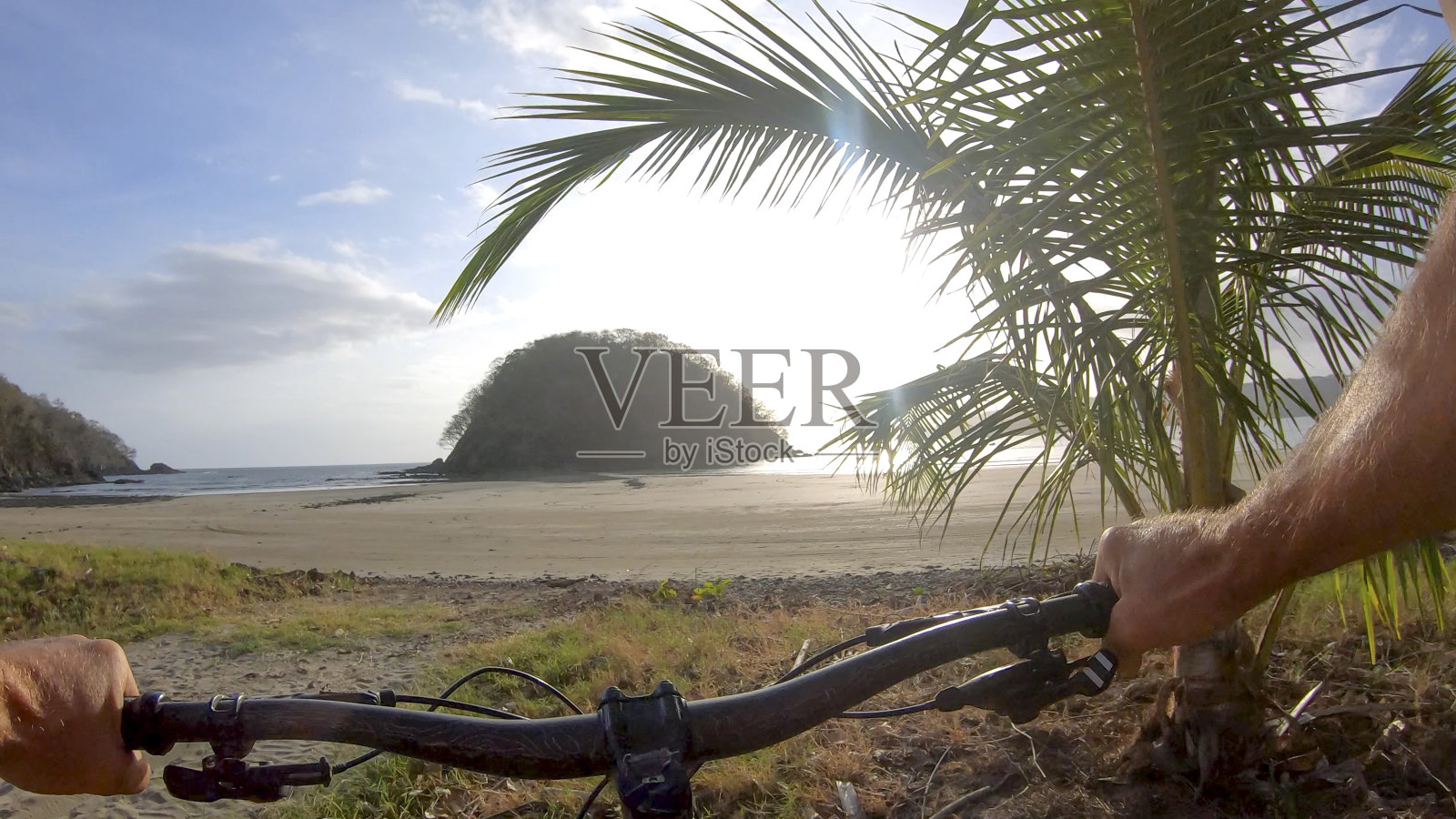 清晨，一名男子骑着山地车沿着沙滩而下照片摄影图片