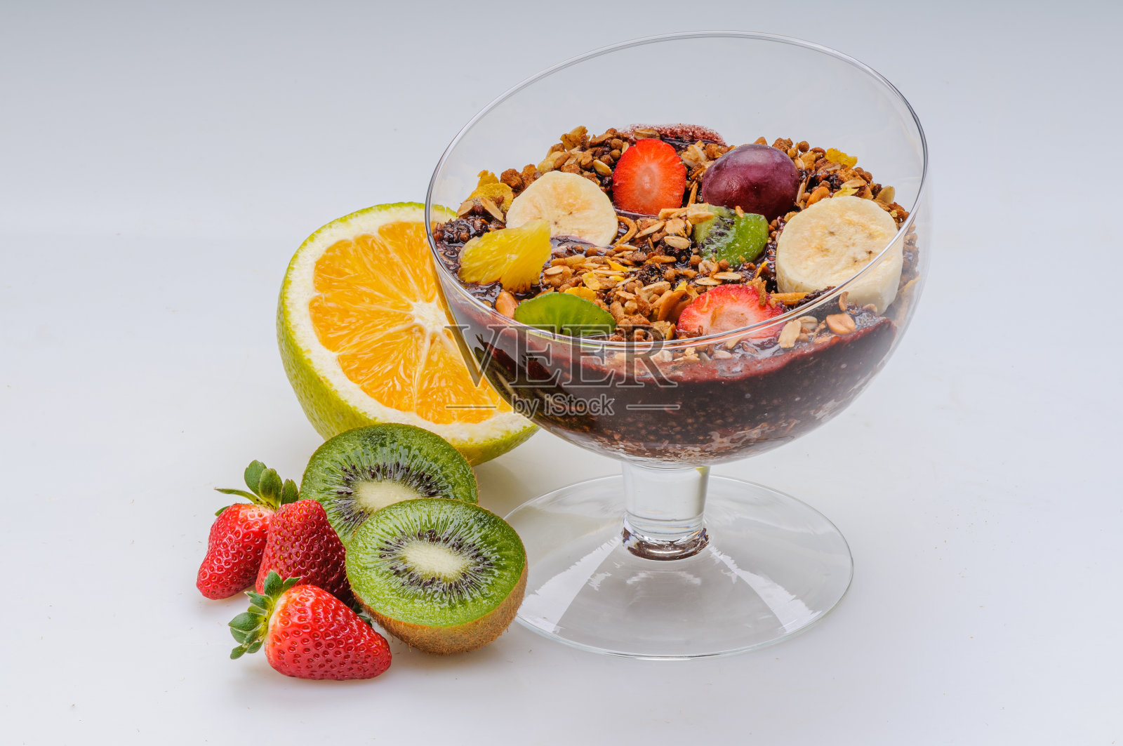 巴西莓与格兰诺拉麦片和水果，如草莓，葡萄，香蕉，木瓜，橙子，猕猴桃在一个玻璃碗在白色的背景。健康食品。照片摄影图片