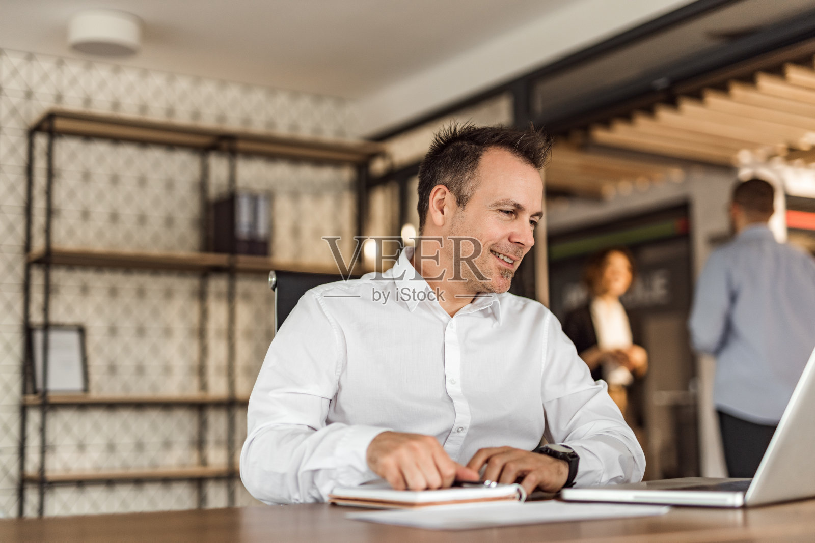 坐在办公桌旁看笔记本电脑的商人，肖像。照片摄影图片