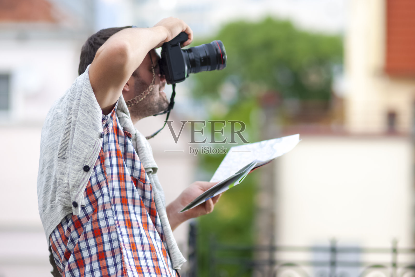 人们旅行。热情的白人男性旅行者用相机拍照的肖像。使用城市地图寻找目的地。照片摄影图片