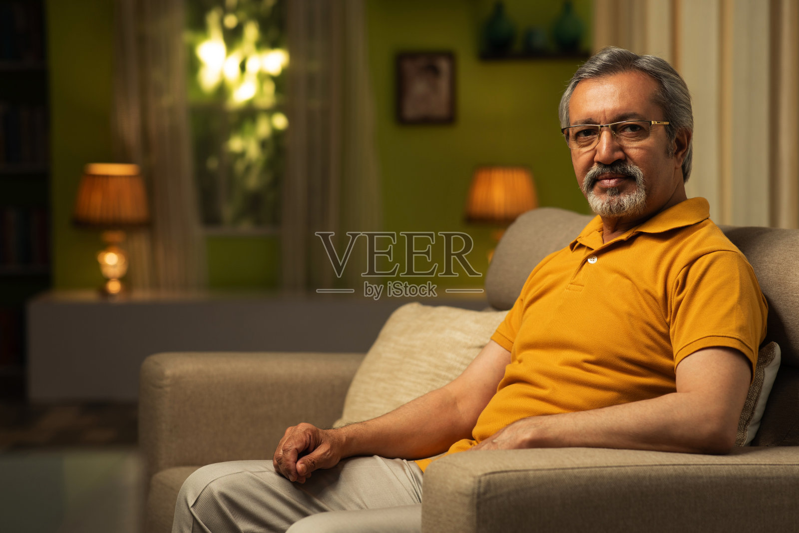 一个成熟的男人坐在沙发上的照片:库存照片照片摄影图片