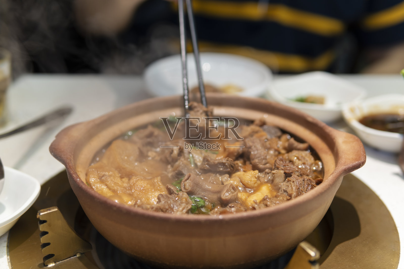 筷子从火锅中夹起一块牛胸肉照片摄影图片