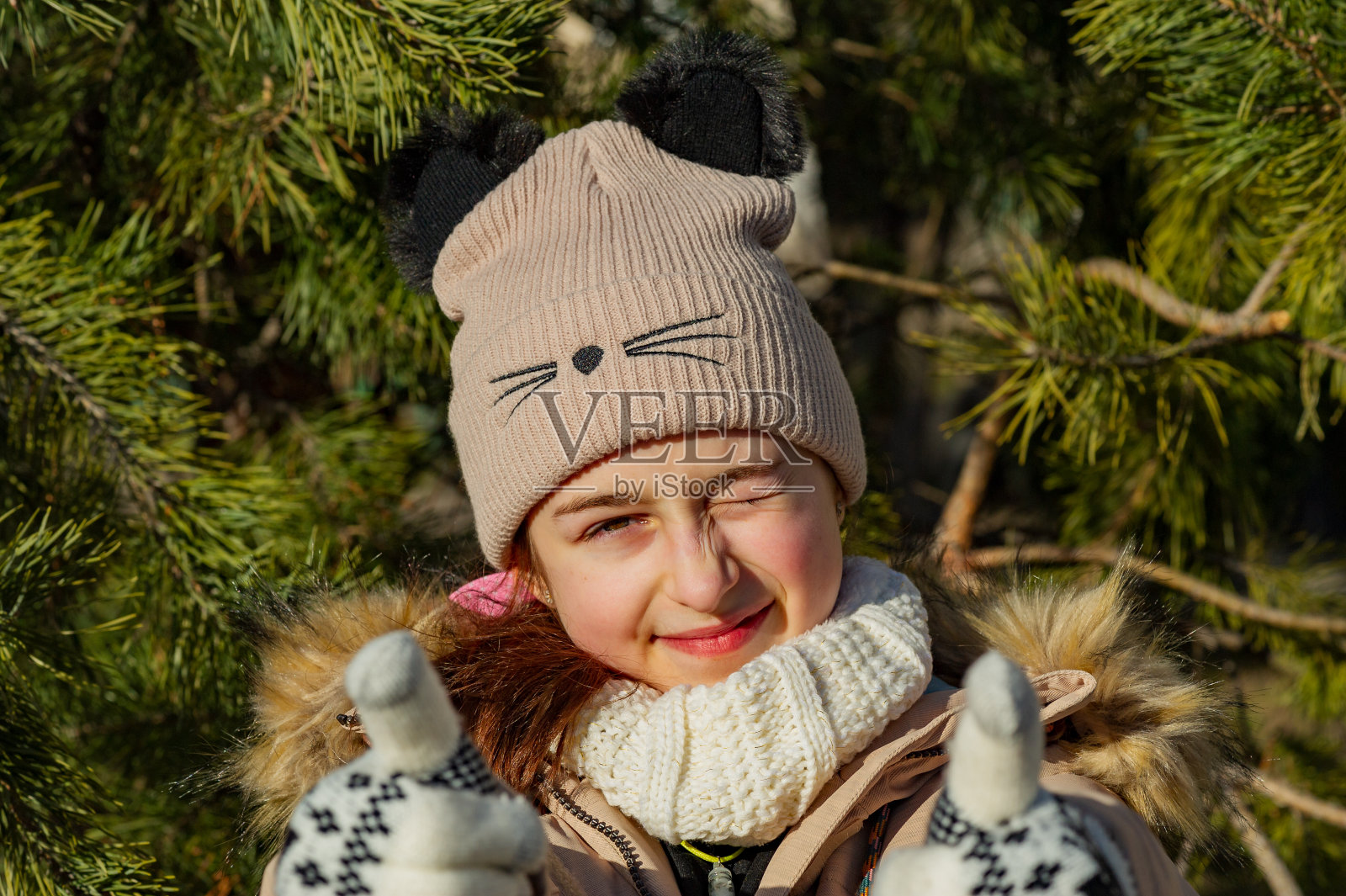 户外肖像可爱的10- 11岁的女孩穿着暖和的夹克，米黄色的帽子和白色的手套。穿着米色夹克的女学生。十几岁的女孩照片摄影图片