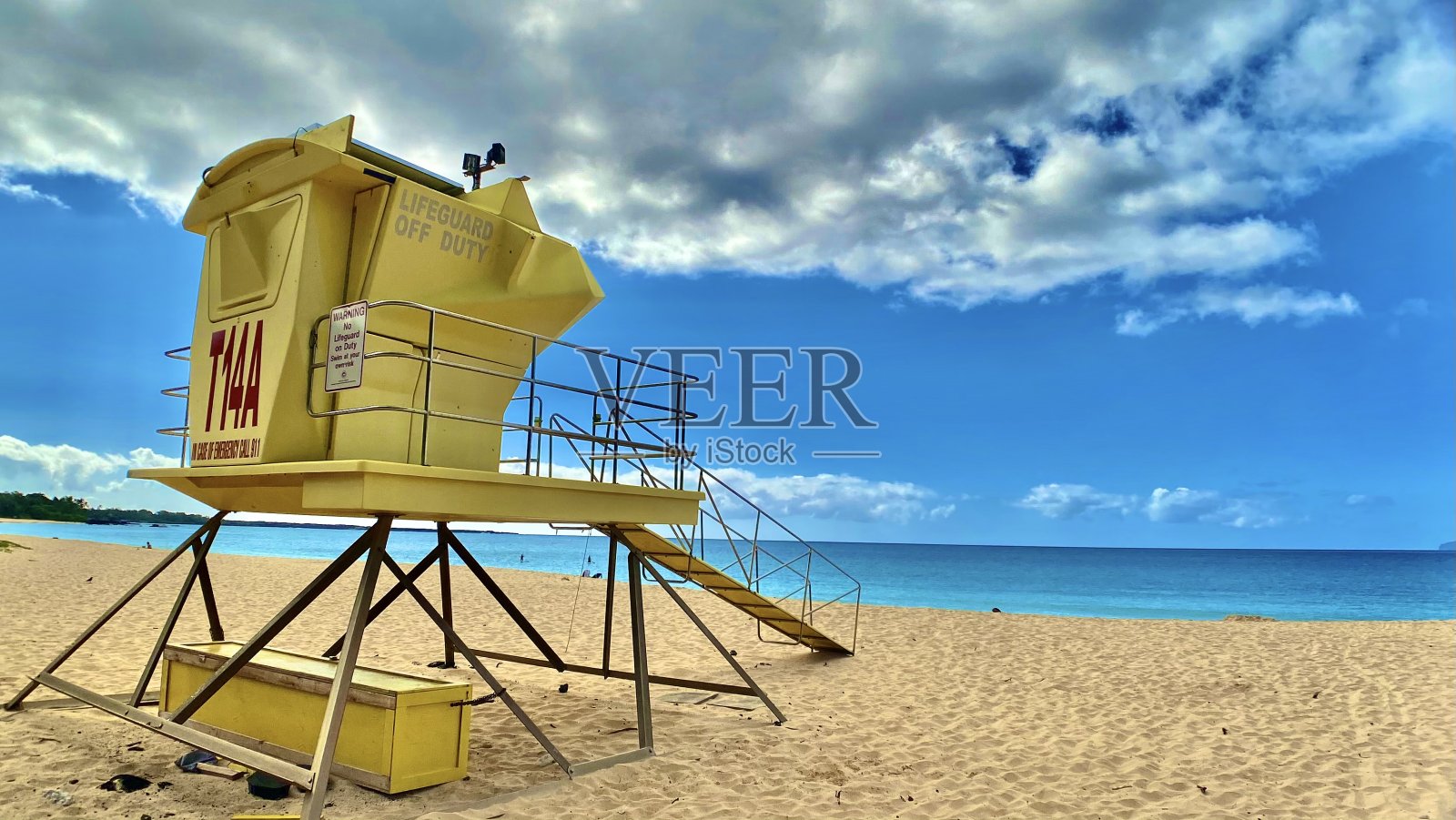 一个黄色的救生员站在蓝天和壮观的云照片摄影图片