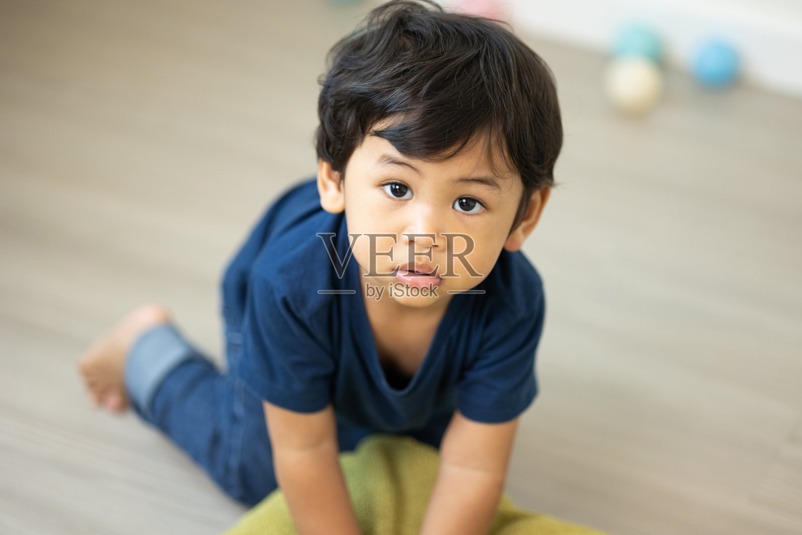 一个大约1岁的亚洲男孩。在房子的客厅里玩。他穿着一件蓝色的衬衫。照片摄影图片