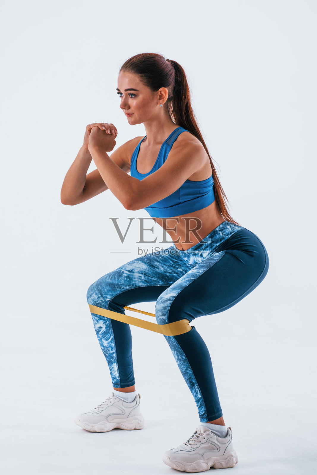 带黄色电阻带。身材苗条的年轻女子被孤立在白色背景下照片摄影图片