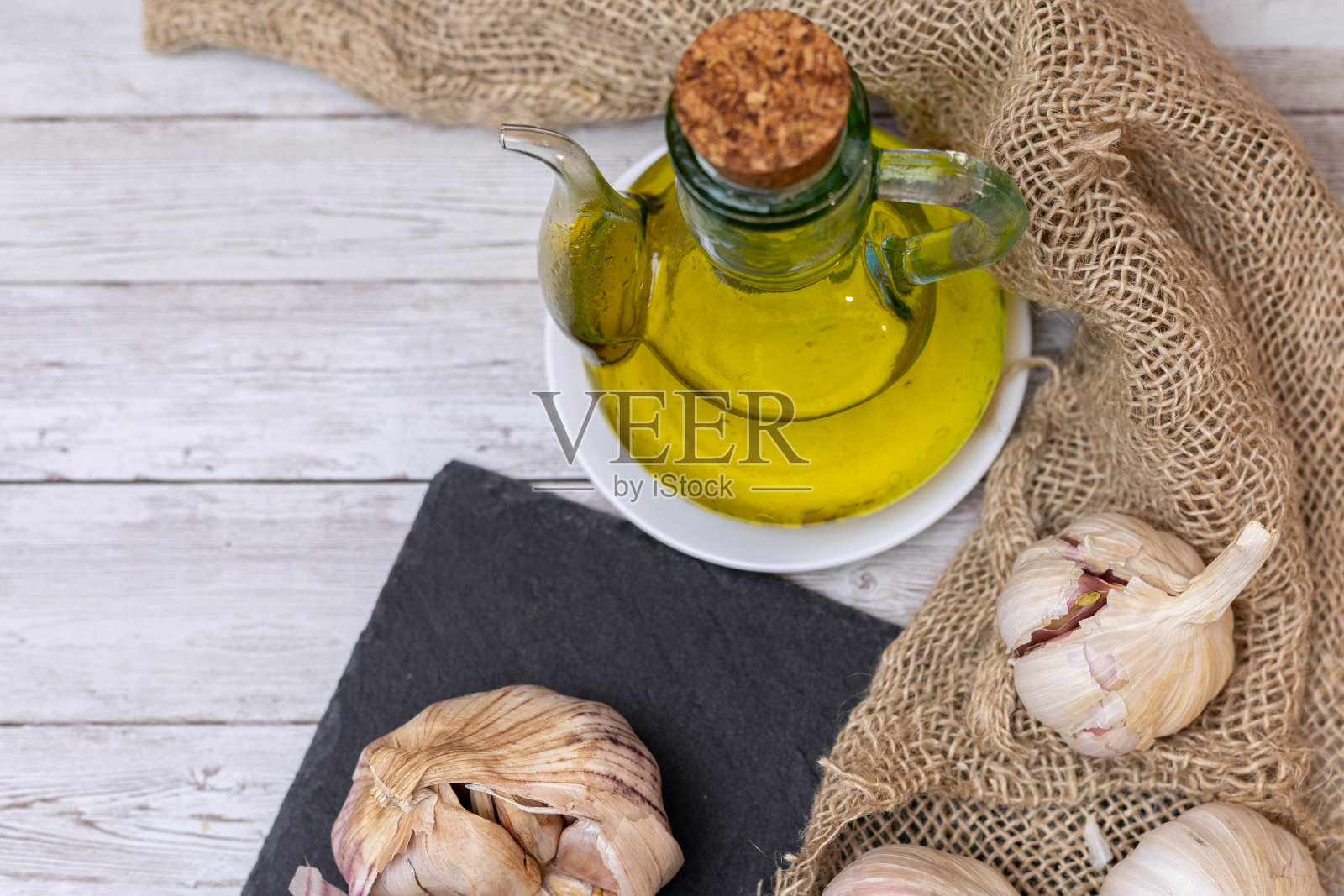 将油和大蒜放在一个罐子里，放在粗麻布和石板板上，准备有拷贝空间的芳香调味品。照片摄影图片