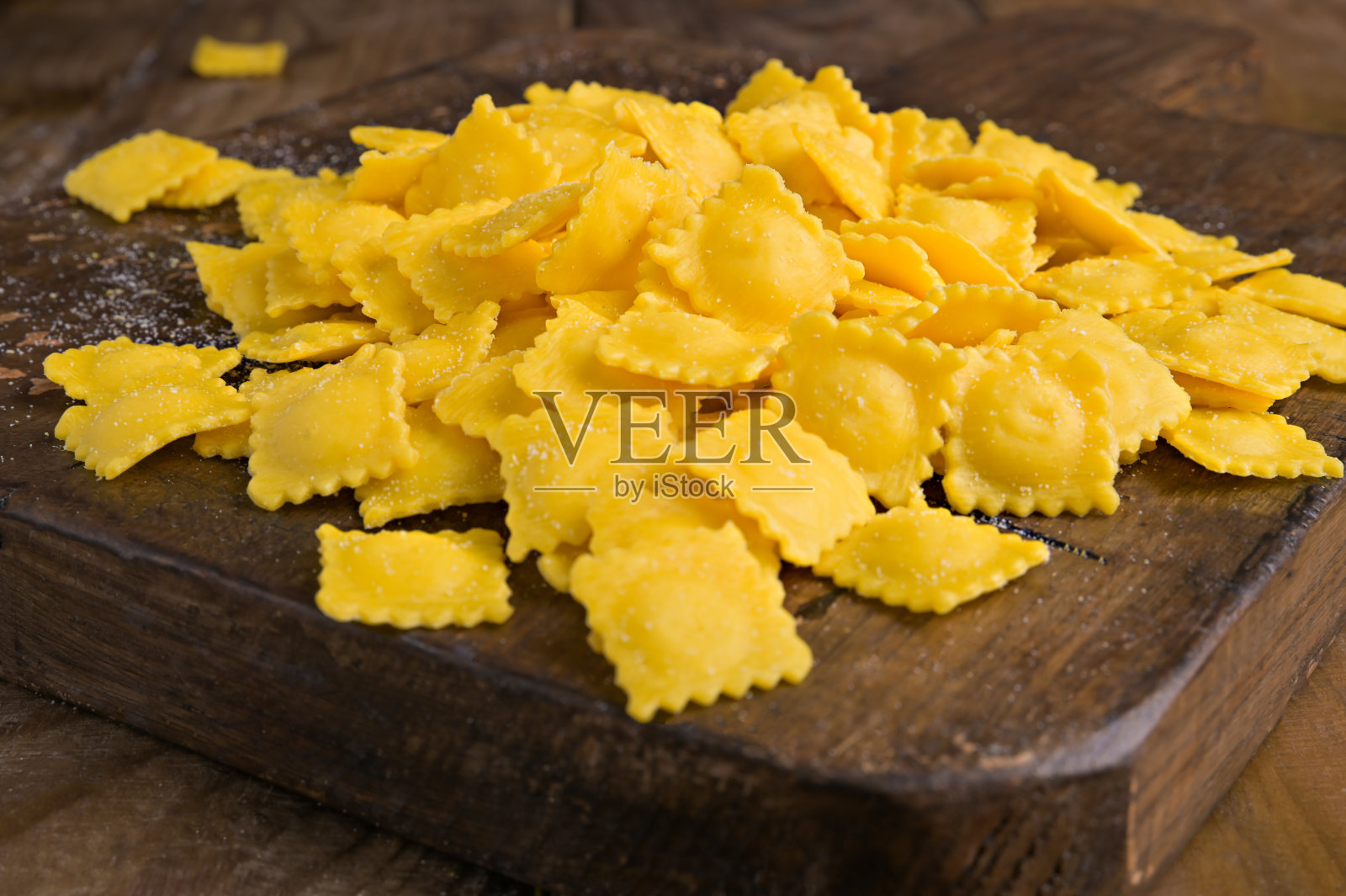 不同形状的意大利塔托里尼，配以奶酪或肉类在肉汤中烹饪。意大利艾米利亚罗马涅地区庆祝节日的传统菜肴。木桌上放着新鲜的自制面食。以上照片摄影图片