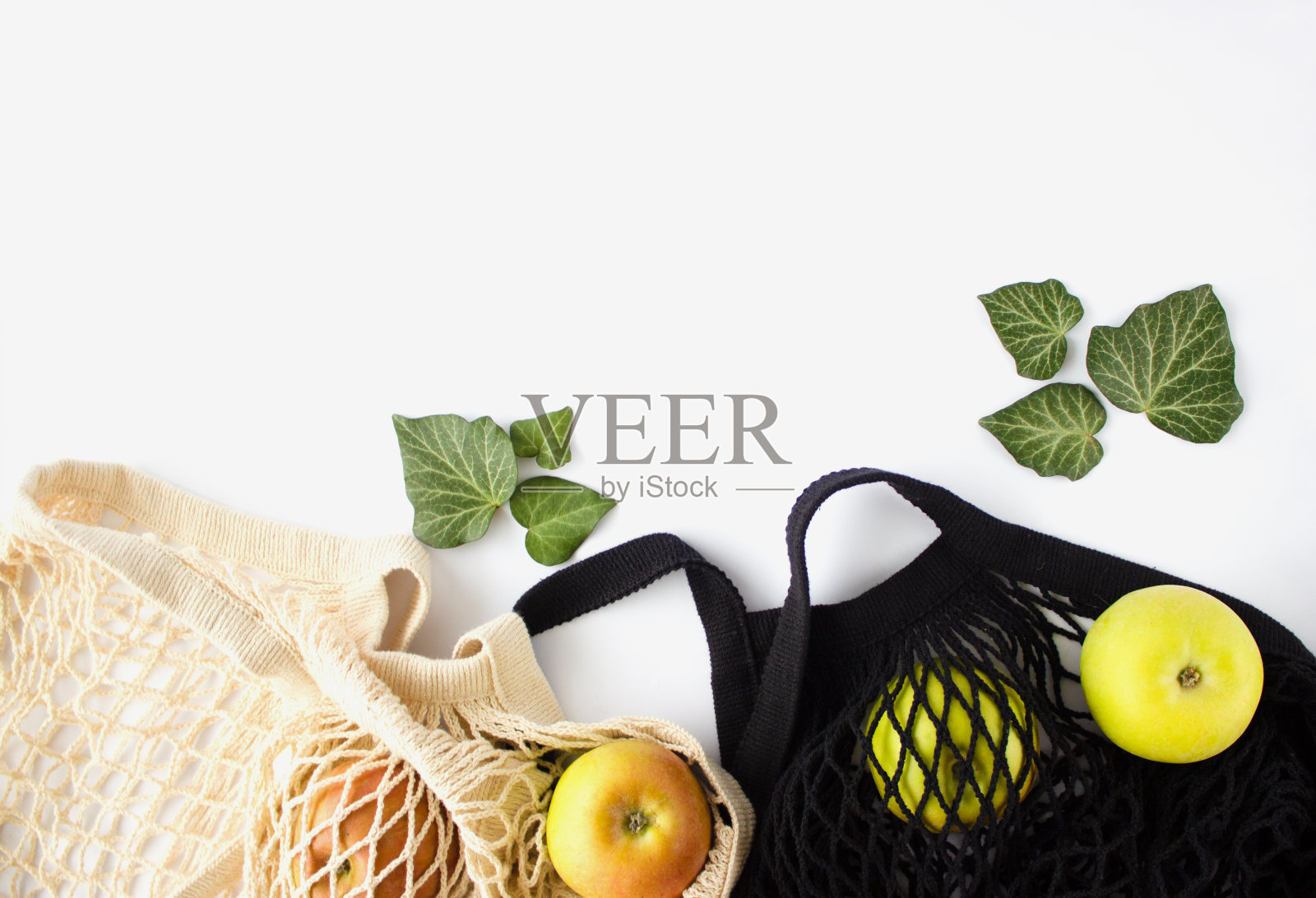 网眼购物袋与青苹果在白色的背景。零浪费购物理念。照片摄影图片