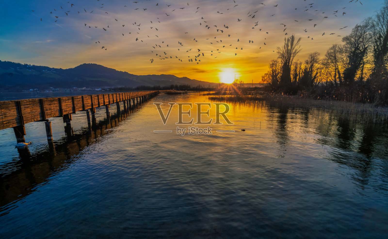 在瑞士Hurden和rapperswill之间的上苏黎世湖(Obersee)岸边的木桥上，美丽的日落照片摄影图片