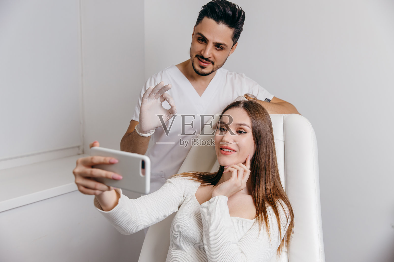 快乐的黑发女人在美容诊所。她正在和医生谈论脸部美容治疗。照片摄影图片