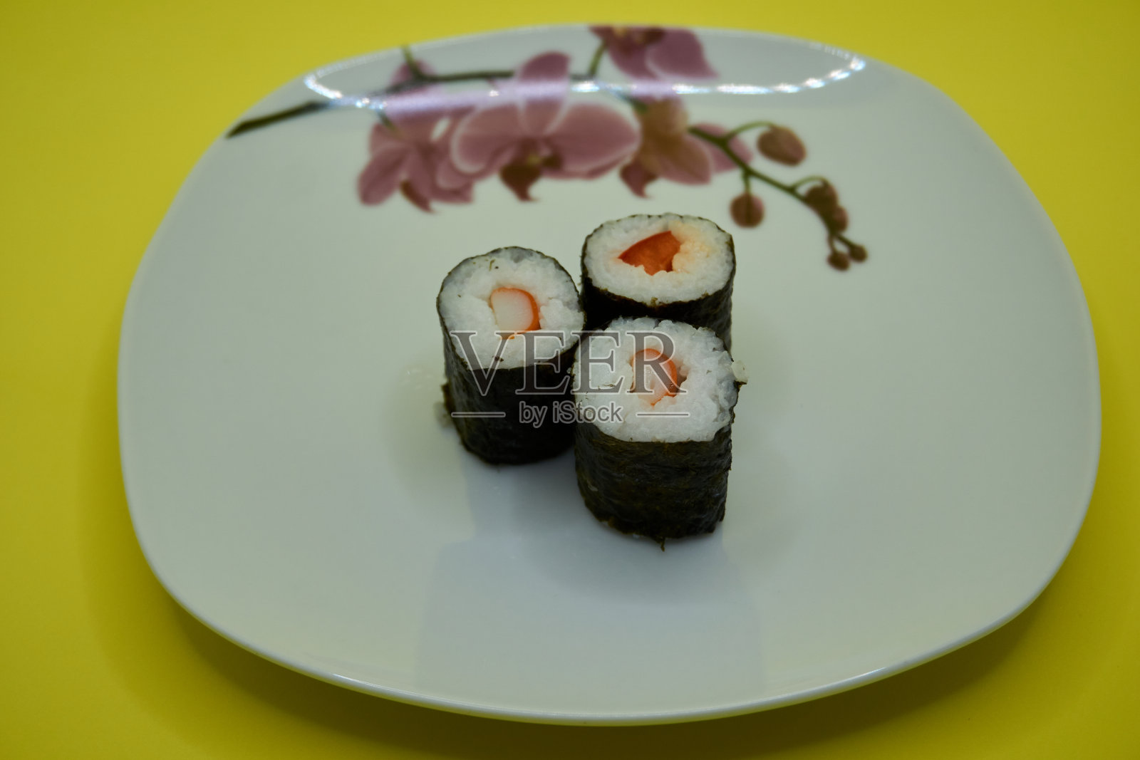 寿司放在黄色背景的瓷盘上照片摄影图片