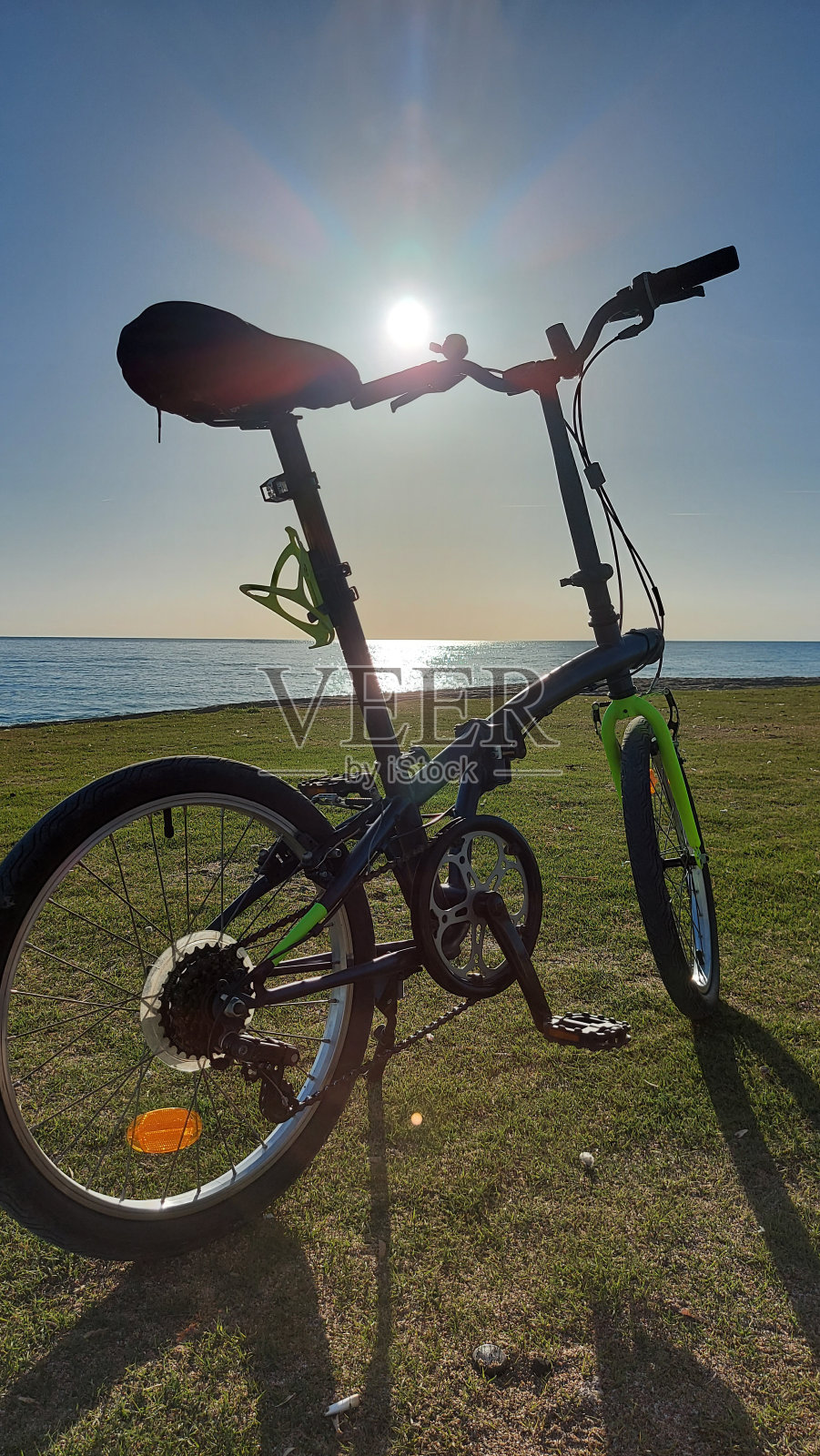 春天，折叠自行车停在海边的水边。照片摄影图片