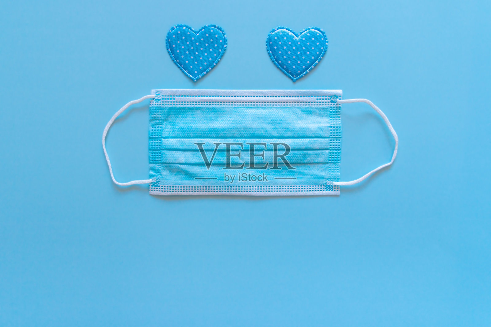 医用防护口罩，蓝色背景上有蓝色心形图案照片摄影图片