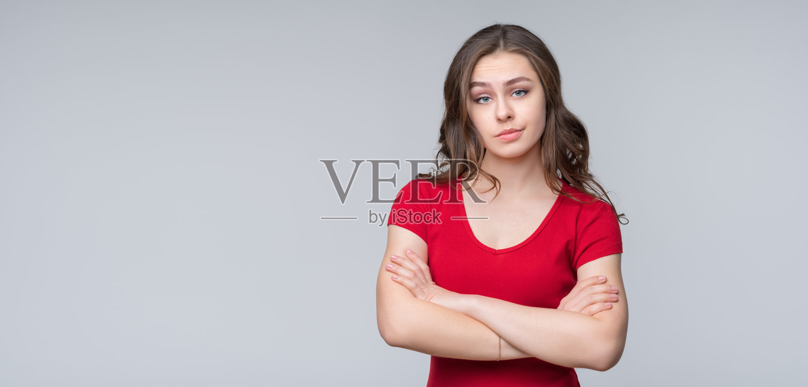 被冒犯的女人的肖像，双手交叉站在灰色的背景。放置文本的位置照片摄影图片