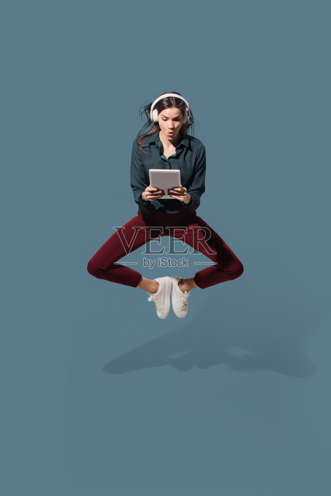 高角度的年轻女子在蓝色的工作室背景。女孩在移动或移动。人类情感和面部表情的概念照片摄影图片