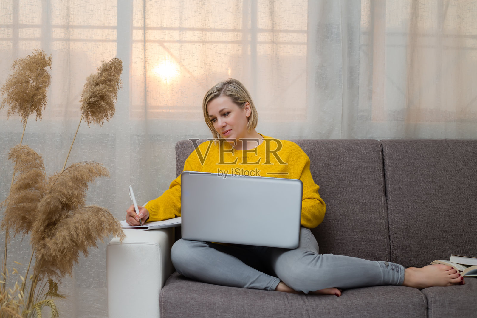 白种女人坐在沙发客厅远程在线工作。2021年的颜色照片摄影图片