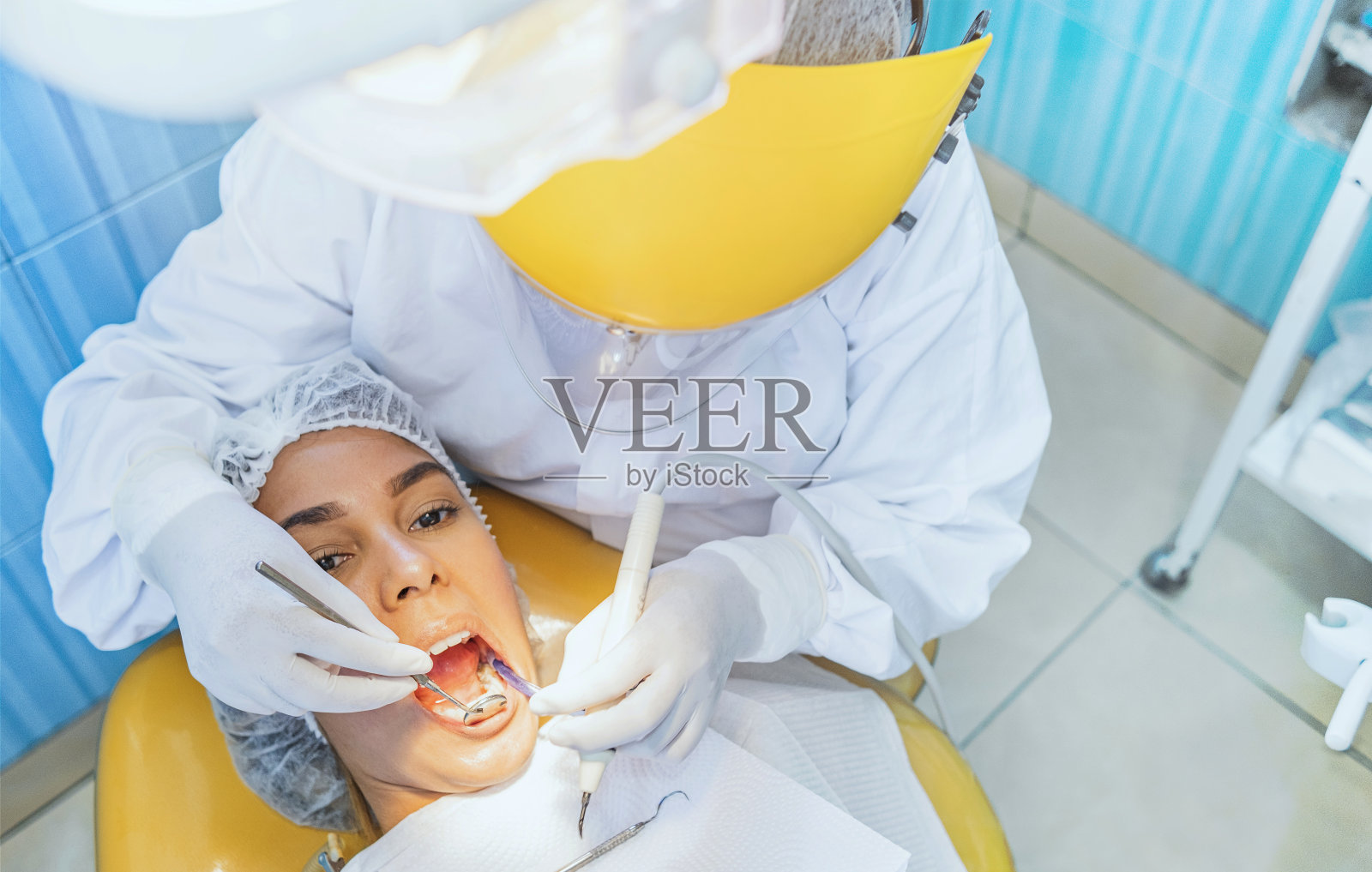 可爱的女人坐在牙医的椅子上，而牙医检查她的牙齿。有选择性的重点。照片摄影图片