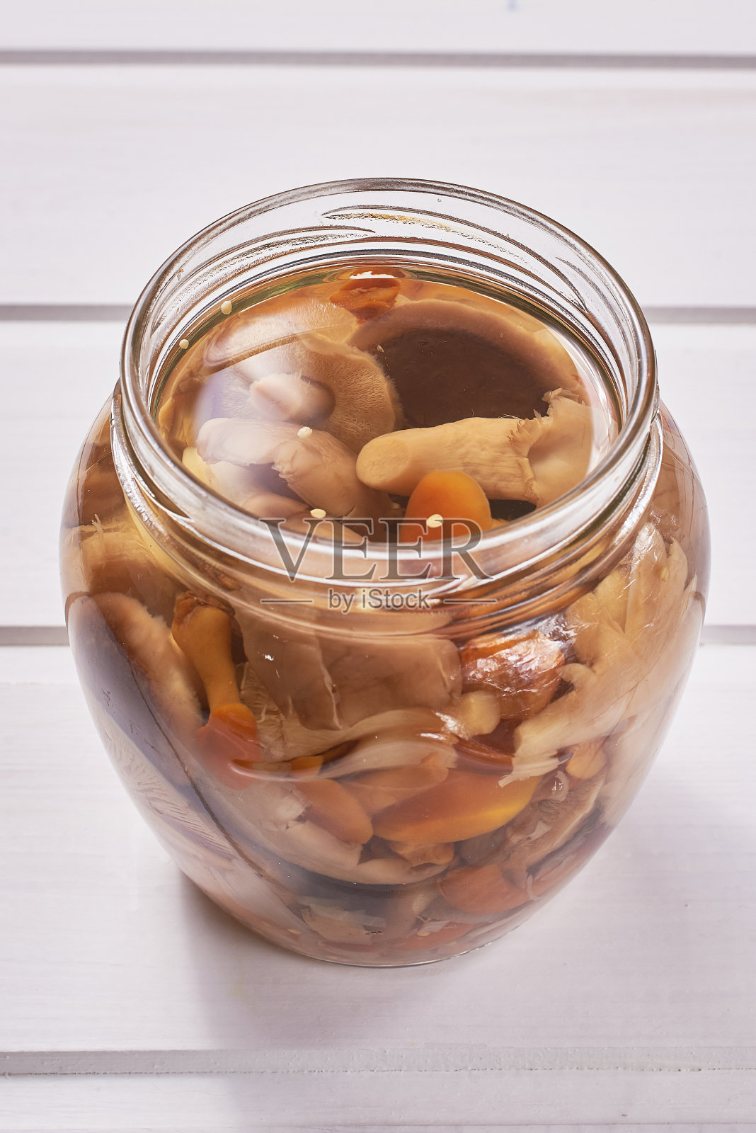 白色木桌上放着一罐自制的腌野蘑菇。俄罗斯传统小吃。特写、宏照片摄影图片