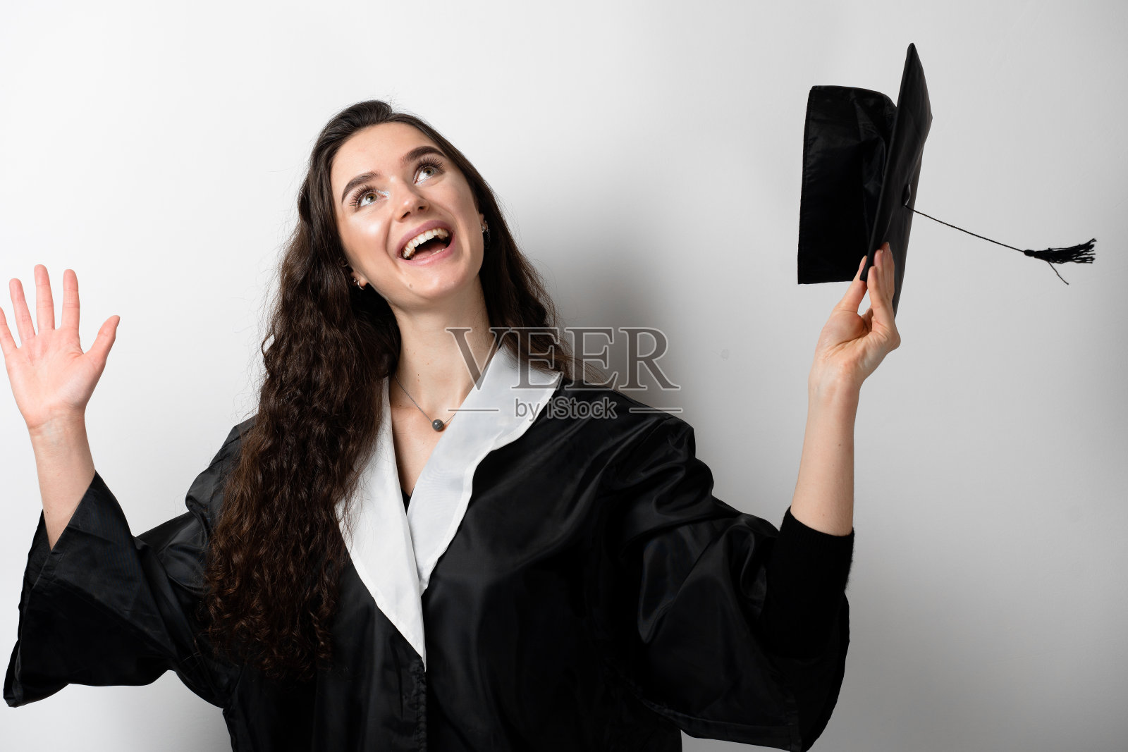 身着黑色毕业礼服，头戴白色学士帽的硕士研究生。网上远程学习。在家里学习。从大学毕业。照片摄影图片