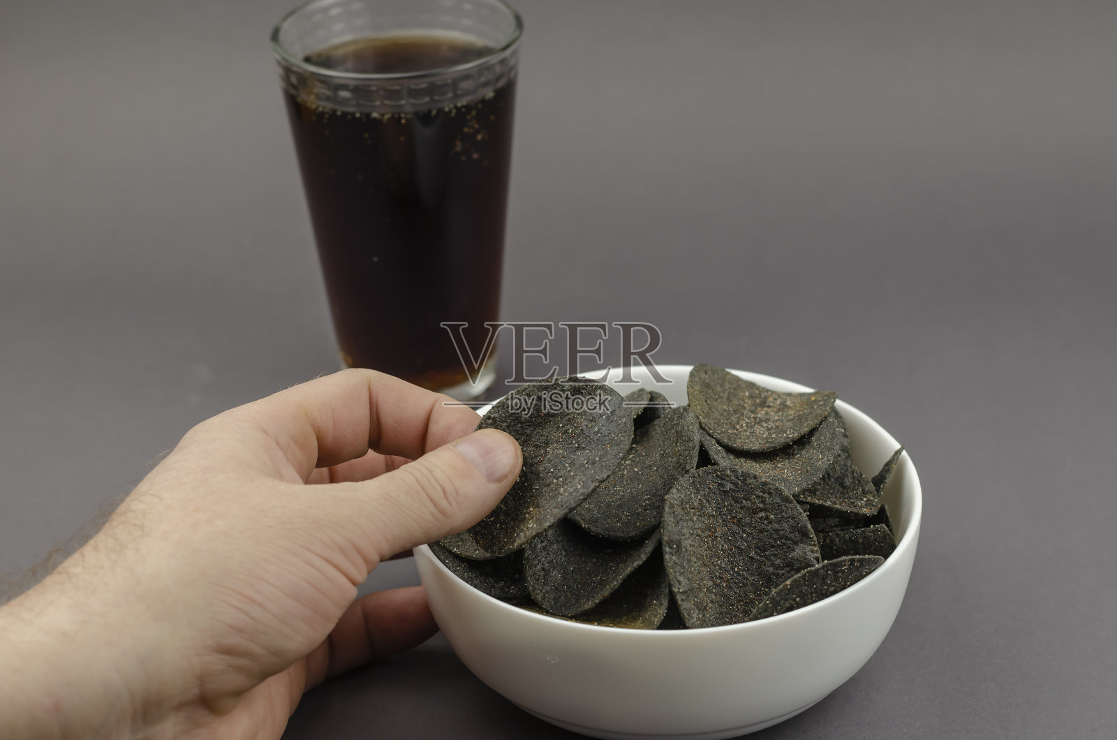 一只手拿着黑色筹码，对着一只白色陶瓷碗和一只玻璃杯照片摄影图片