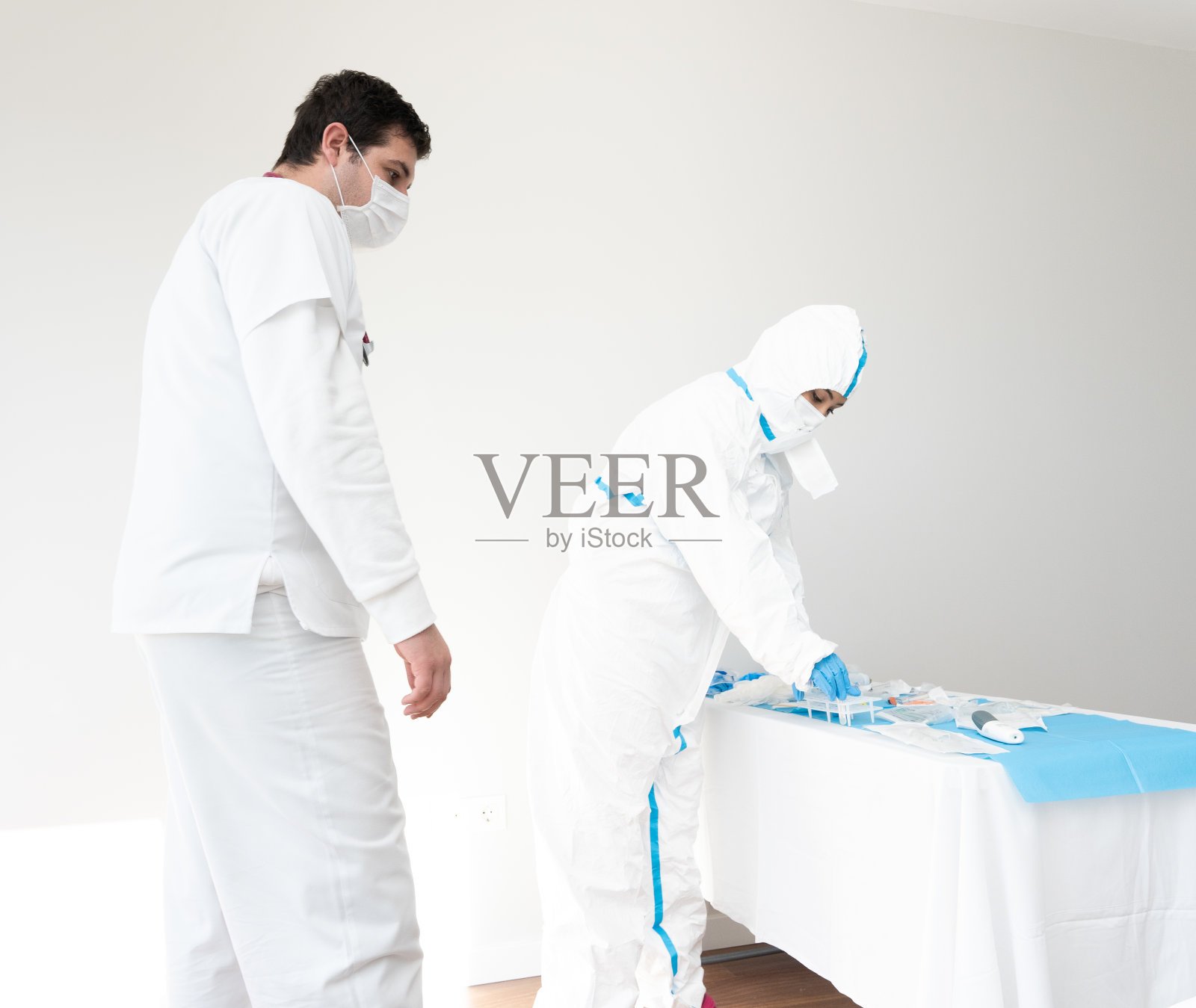 身穿防护服的医生与同事在医务室工作照片摄影图片