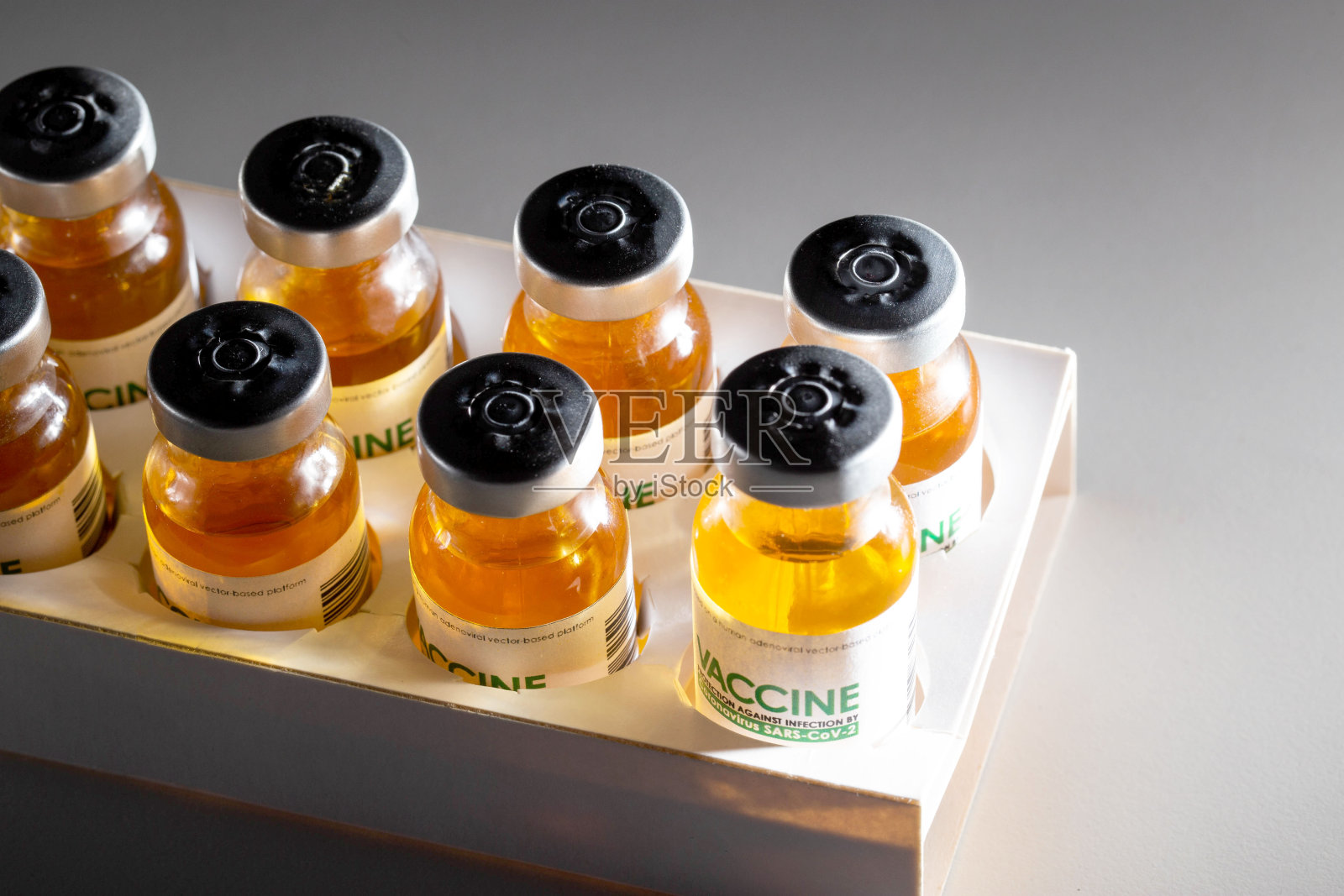 装有冠状病毒疫苗的包装瓶置于黑色背景上，并被一束光照亮。人群接种疫苗配方、疫苗研究、SARS-Cov-2照片摄影图片