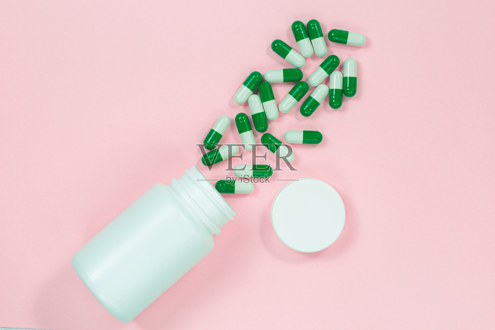 酸奶胶囊在一个玻璃瓶浅粉红色的背景与复制空间为您的文本。粉红色背景的白色益生菌胶囊。模板医疗博客社交媒体。照片摄影图片