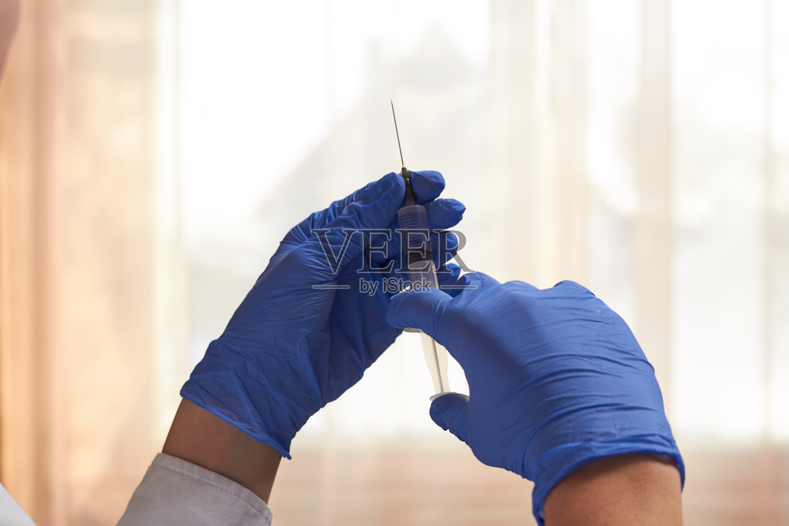 一位戴着蓝色医用手套的医生双手拿着医用注射器。照片摄影图片