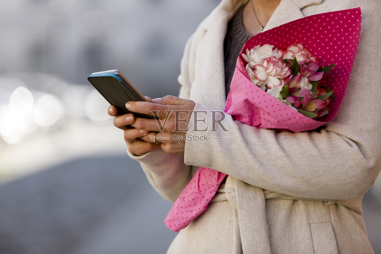 一个女人拿着一束粉色的花，正在发短信照片摄影图片