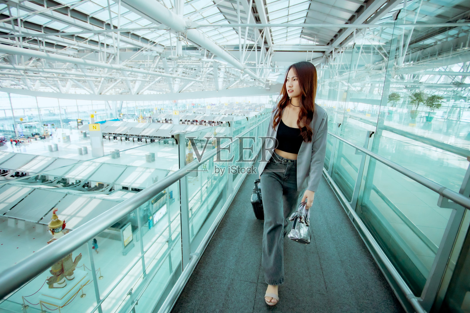 一个年轻的亚洲女人在机场拖着行李照片摄影图片