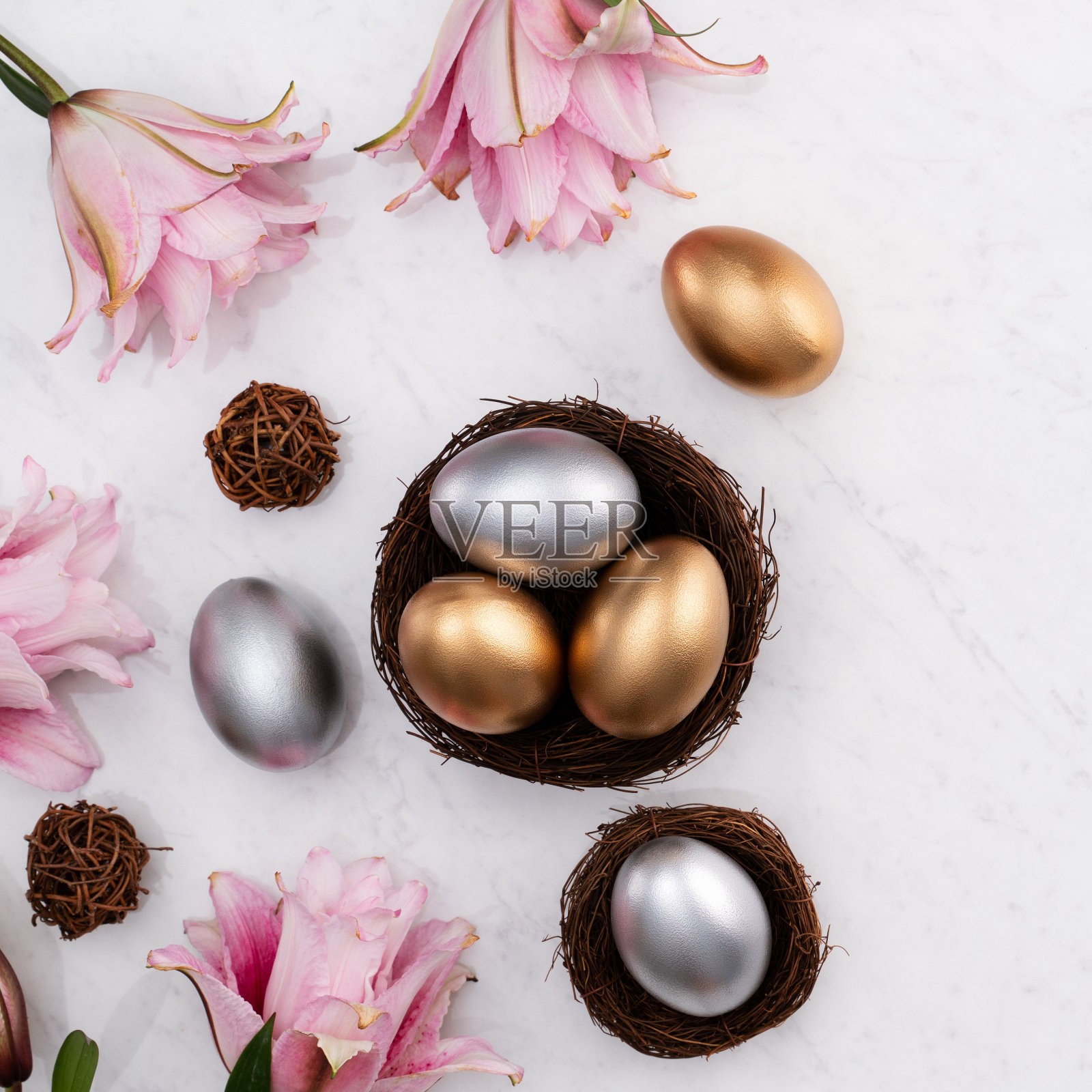 金、银复活节彩蛋的设计理念与粉色百合花的巢。照片摄影图片