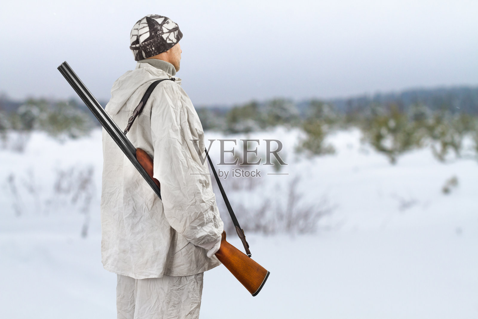 冬天打猎时，肩上扛着猎枪的猎人照片摄影图片