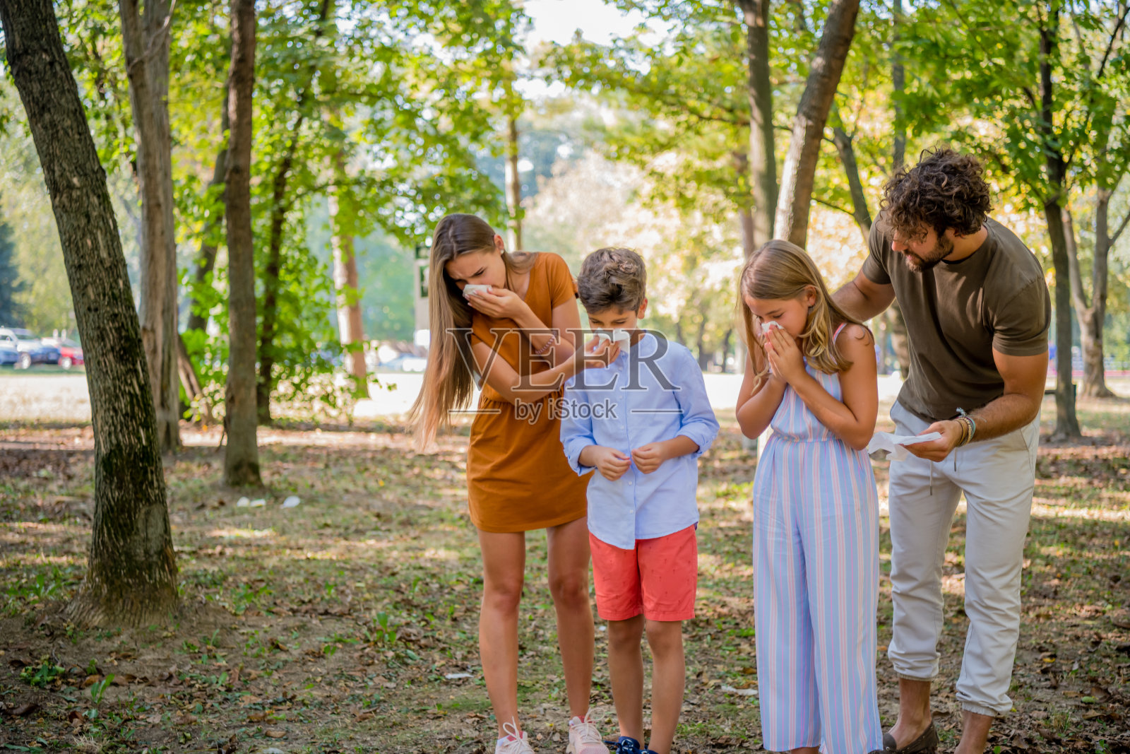 在户外打喷嚏和咳嗽的患流感和高烧的生病家庭照片摄影图片